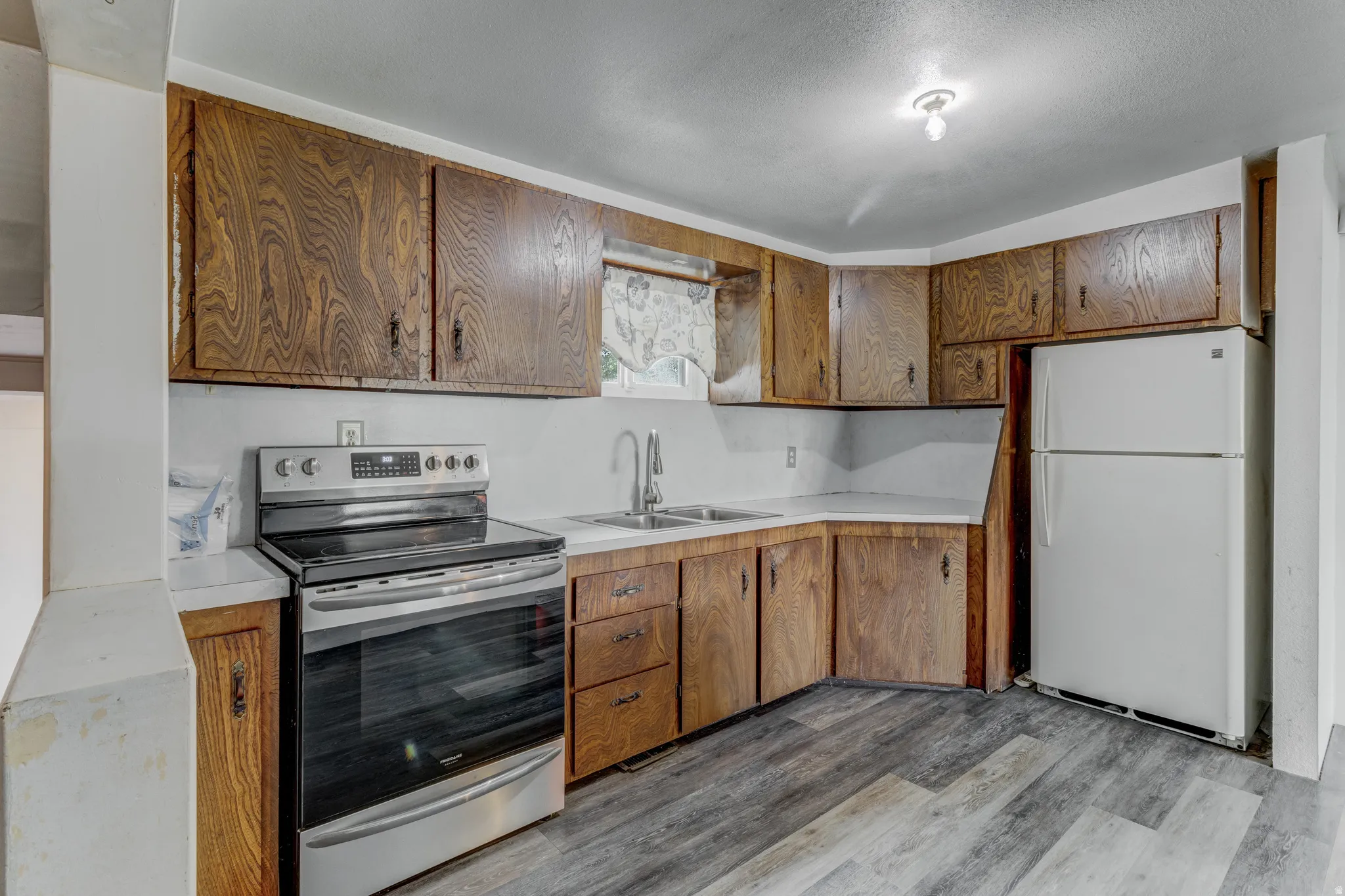 Wood-finish cabinetry paired with white countertops and a stainless steel electric range