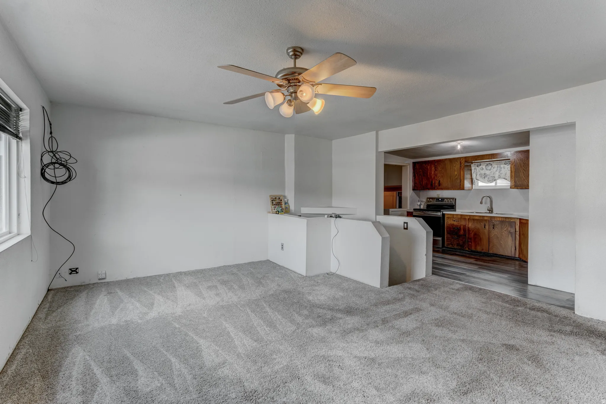 Carpeted living area featuring a ceiling fan with integrated lighting