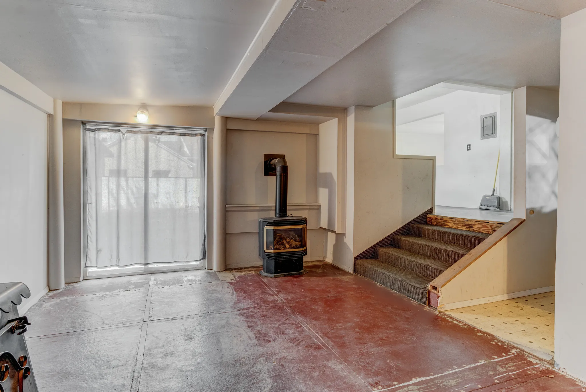 Wood-burning stove, exposed ceiling beams, and concrete flooring