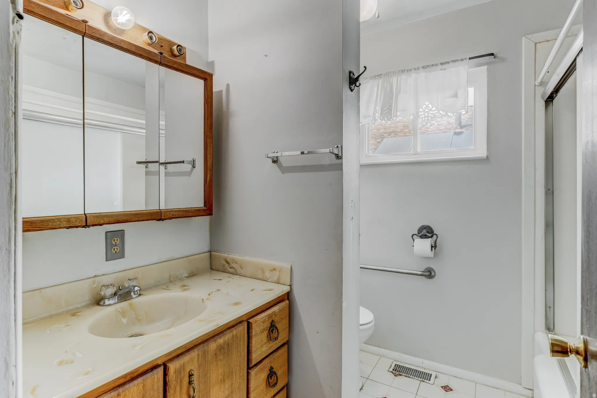 Vanity with an integrated sink and wood-finish cabinetry, illuminated by a multi-bulb light fixture