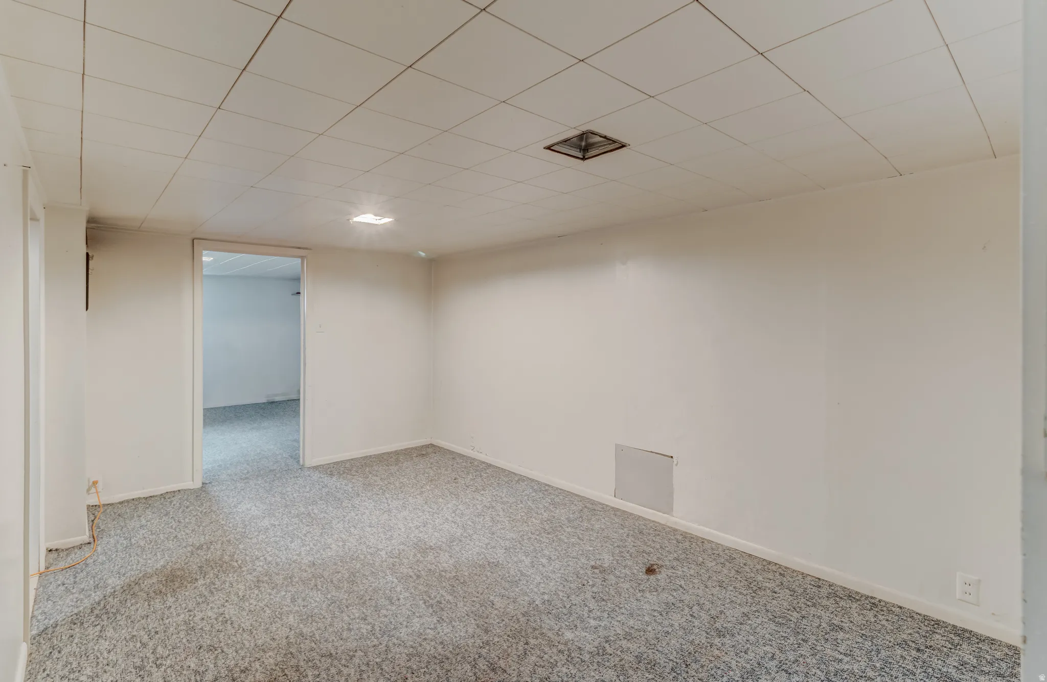 Recessed lighting illuminating a carpeted room with white walls and a drop ceiling