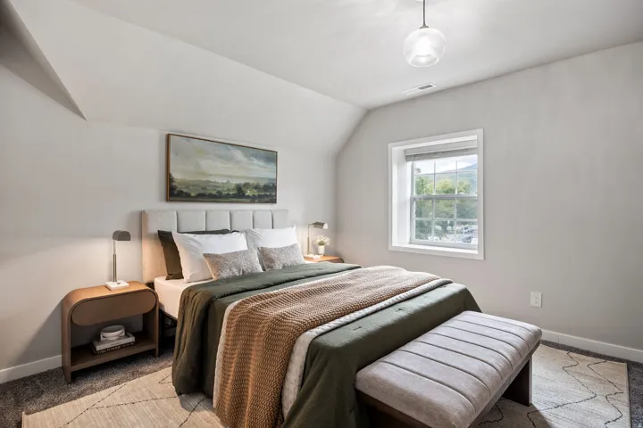 Pitched ceiling with a contemporary pendant light fixture, window with roller shade, and light gray wall paint
