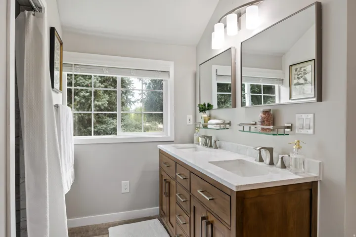 Dual vanity with wood-finish cabinetry, white stone countertop, and undermount sinks
