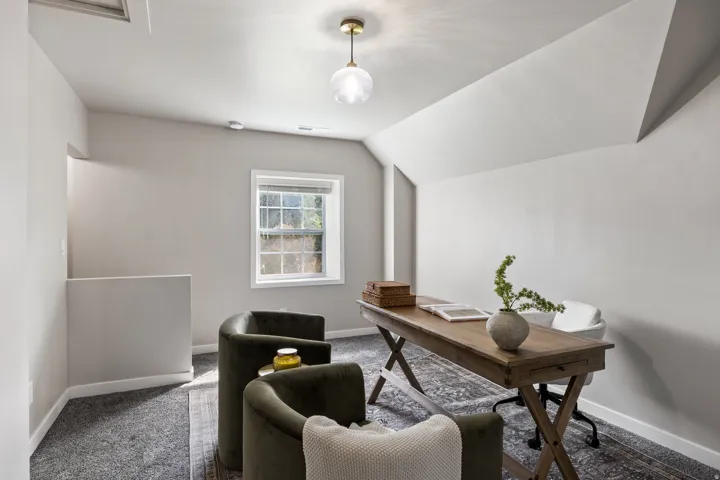 Vaulted ceiling with an attached light fixture, a window with natural light, and sloped walls