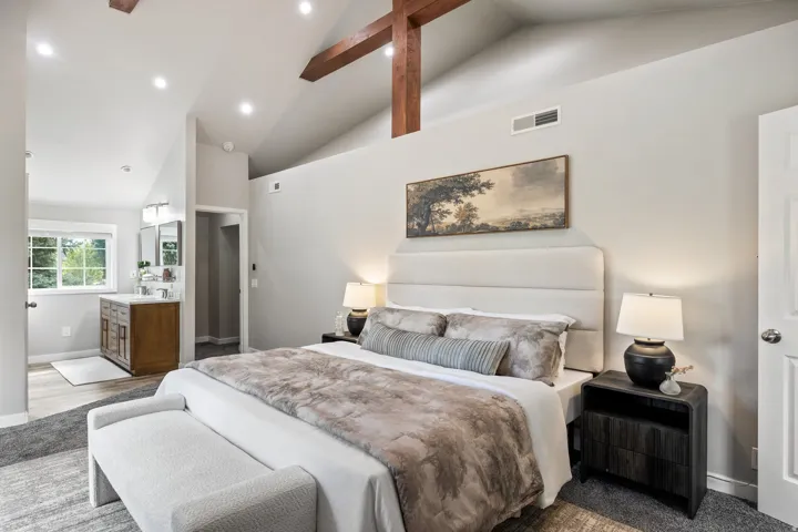Vaulted ceilings with exposed wood beams, recessed lighting, and soft gray wall tones