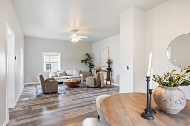 Spacious interior with vaulted ceilings, wood-finish flooring, a ceiling fan, and multiple windows providing natural light