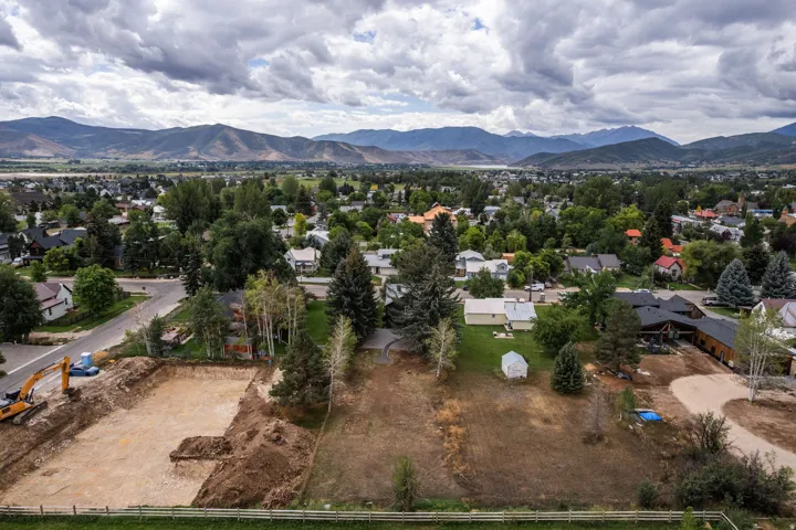 Expansive lot with a cleared building site, existing mature trees, and mountainous terrain in the background