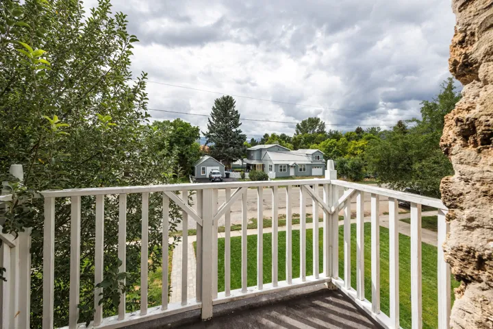 Balcony featuring white wooden railing and a textured stone-finish wall
