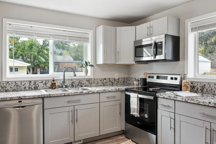 Contemporary kitchen featuring light gray cabinetry, stainless steel appliances, a double basin sink, and ample countertop space