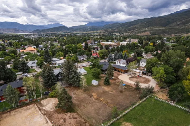 Expansive property with a large undeveloped lot, mature trees, and mountainous terrain in the background