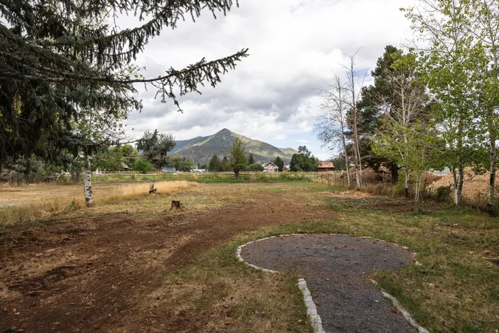 Expansive lot featuring mature trees, a gravel pathway, and distant mountain scenery
