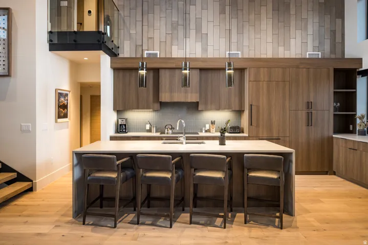 Gourmet kitchen featuring a large central island, integrated appliances, wood-finish cabinetry, and a full-height tile backsplash