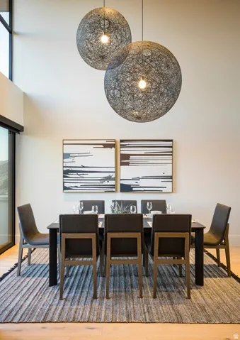 Dining area featuring soaring ceilings with statement spherical pendant lighting, light wood-finish flooring, and a sliding glass door