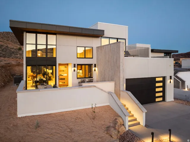 Contemporary architectural residence featuring a prominent two-story window array, a light wood-finish entry door, and a black garage door with horizontal frosted glass inserts