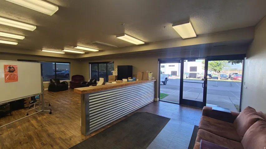 Corrugated metal and wood-finish reception counter, wood-finish flooring, multiple windows, recessed lighting, and a glass-paneled entry door