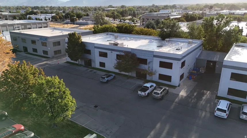 Two-story commercial building with multiple windows, a flat roof, and an adjacent paved parking area