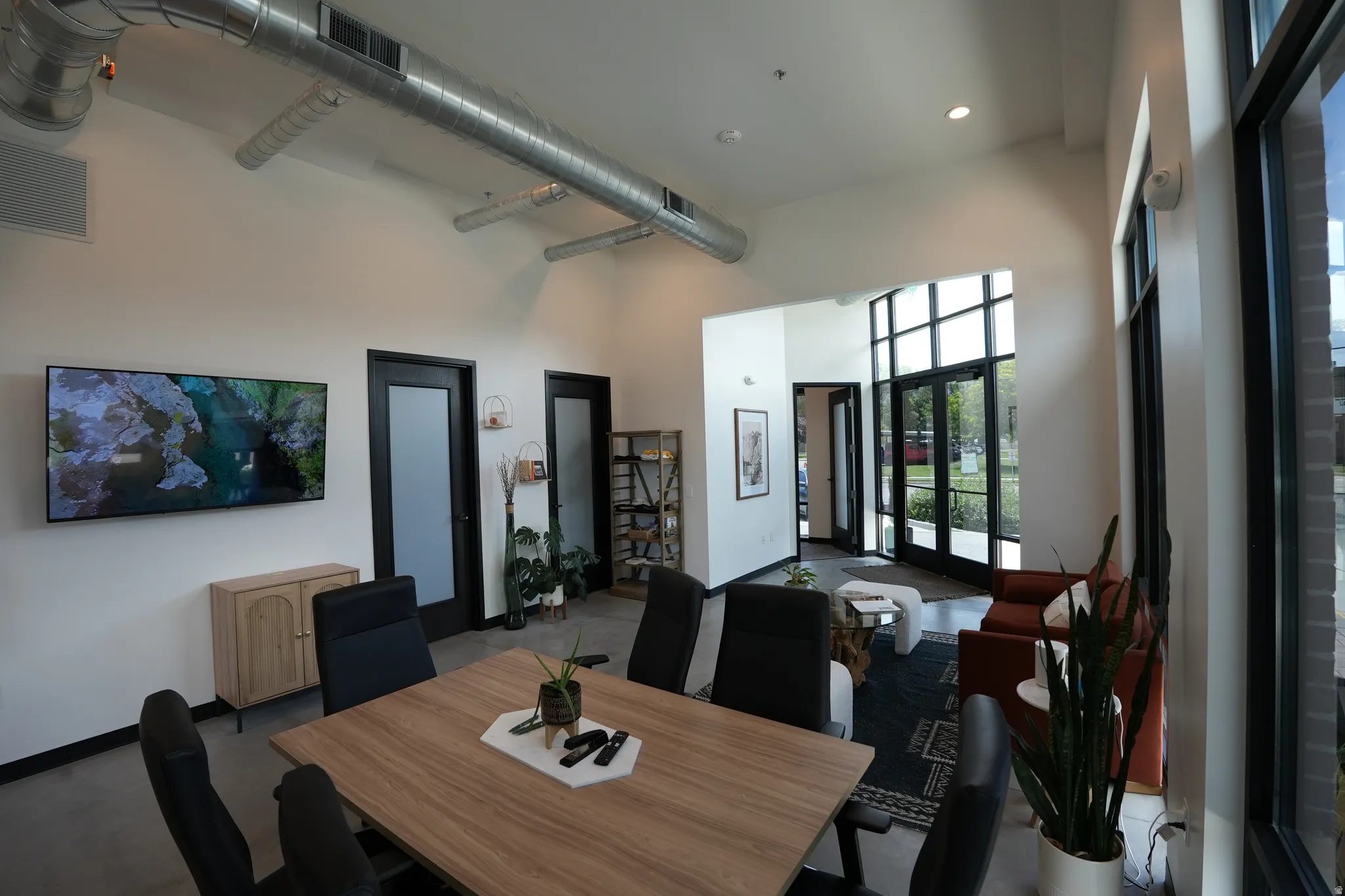 High vaulted ceiling with exposed ductwork, large paneled windows, double entry doors, wood-finish flooring, and recessed lighting