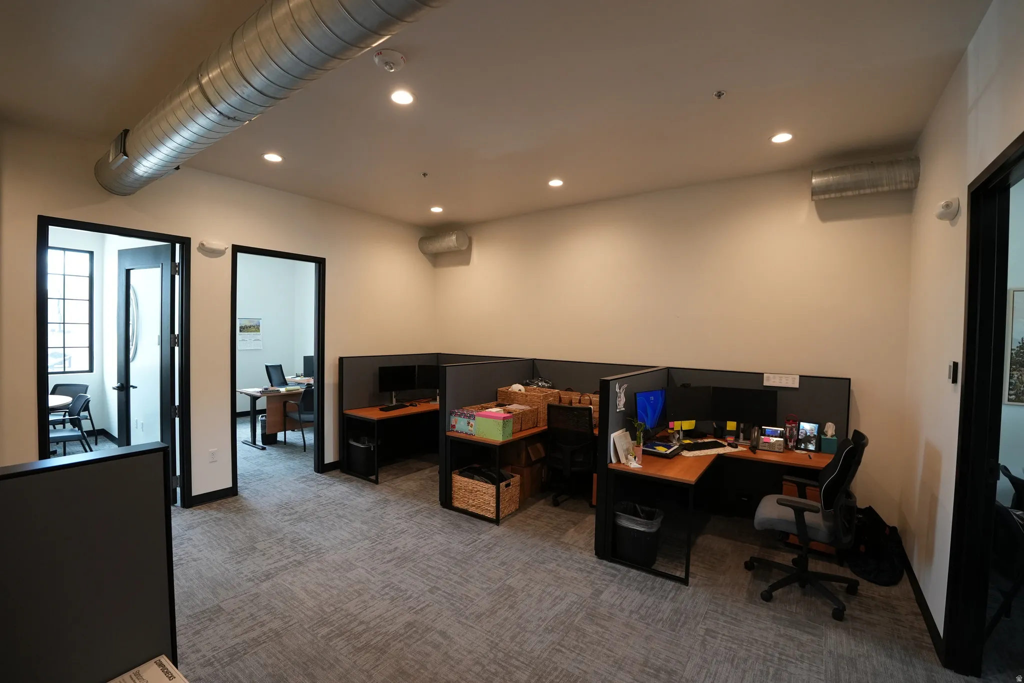 Recessed lighting, exposed ductwork, gray patterned carpet, and multiple framed doorways