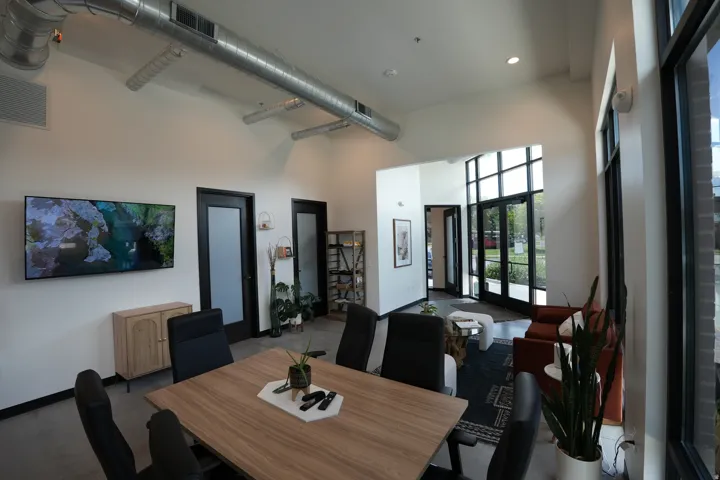High vaulted ceiling with exposed ductwork, large paneled windows, double entry doors, wood-finish flooring, and recessed lighting