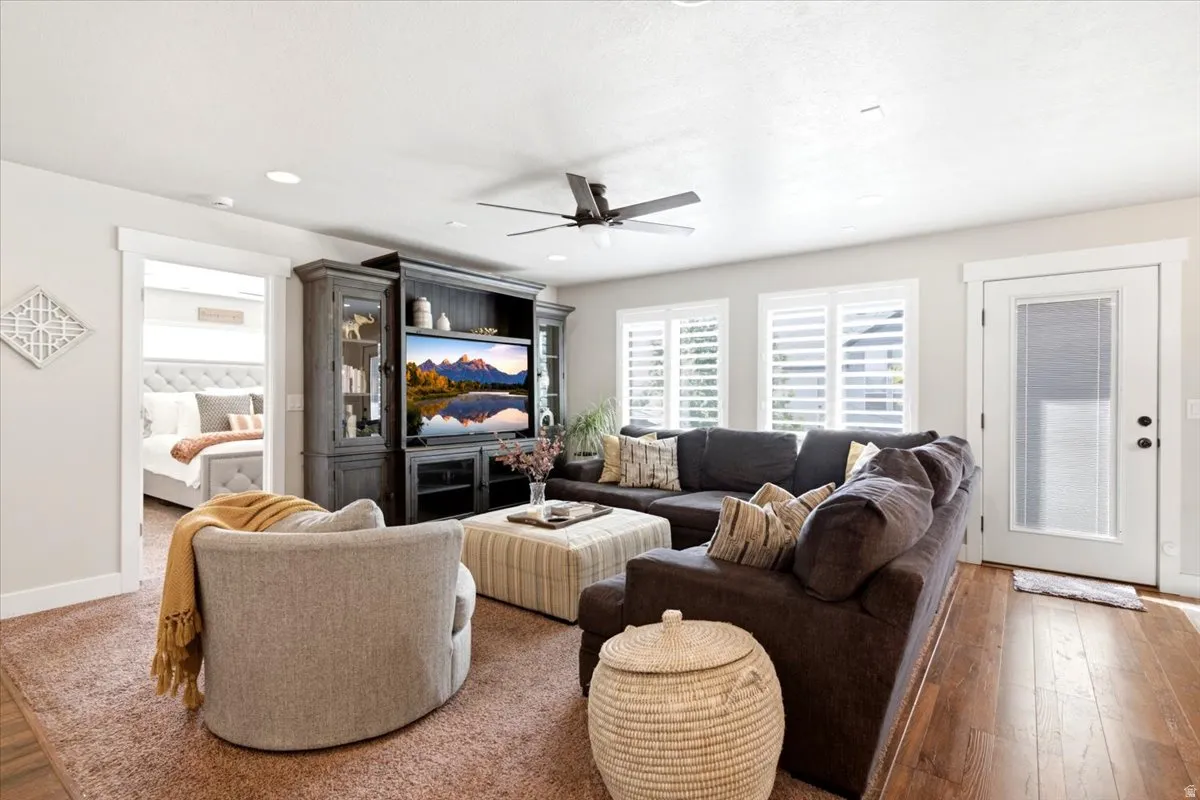 Recessed lighting, wood-finish flooring, ceiling fan, white window shutters, and a built-in media center