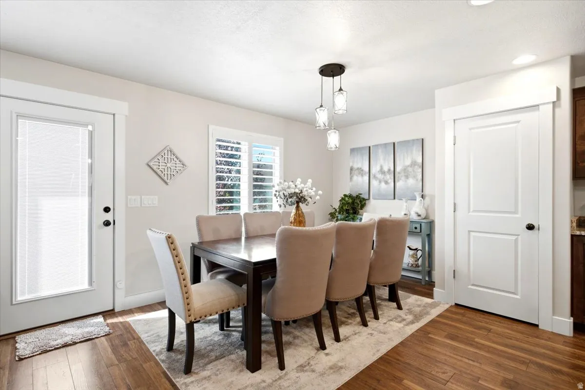 Wood-finish flooring, white window shutters, and a three-light pendant fixture