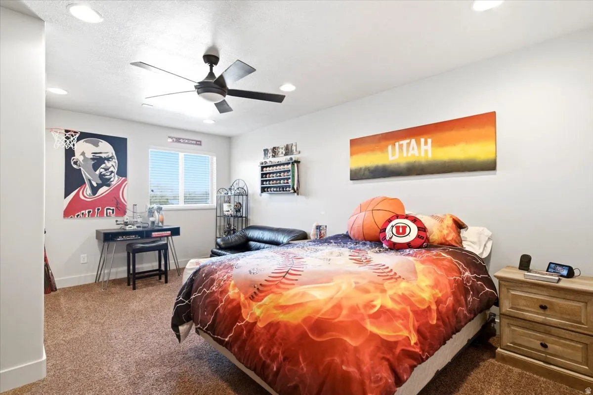 Recessed ceiling lighting, ceiling fan fixture, neutral wall paint, single window with blinds, and brown carpet flooring
