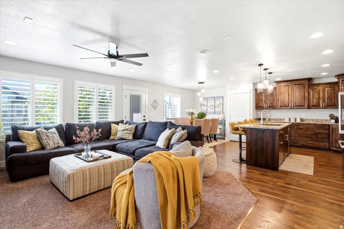 Recessed lighting, wood-finish flooring, kitchen island with seating, pendant lighting, and white plantation shutters
