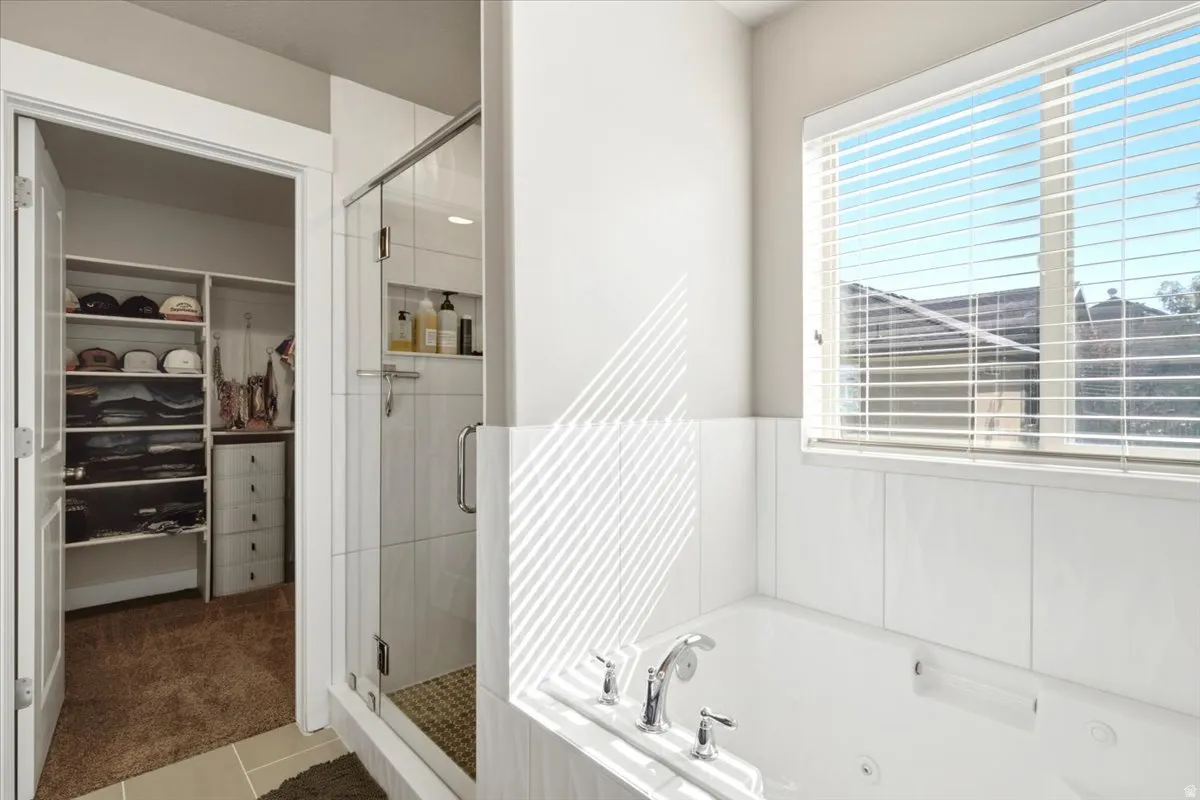 Soaking tub with chrome fixtures, tiled surround, and integrated window