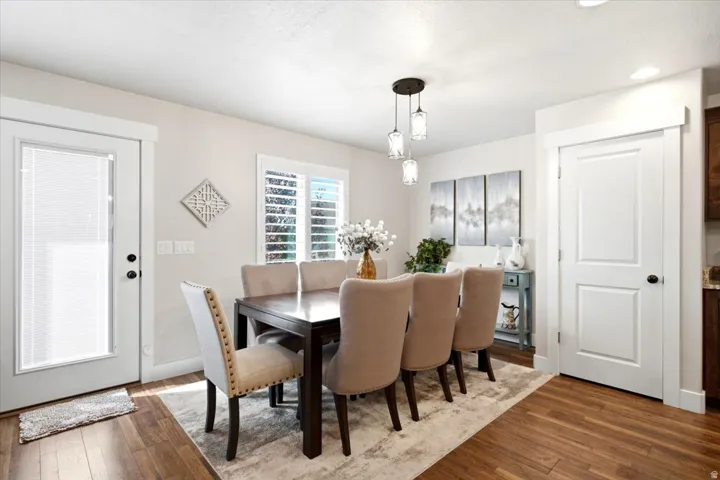 Wood-finish flooring, white window shutters, and a three-light pendant fixture