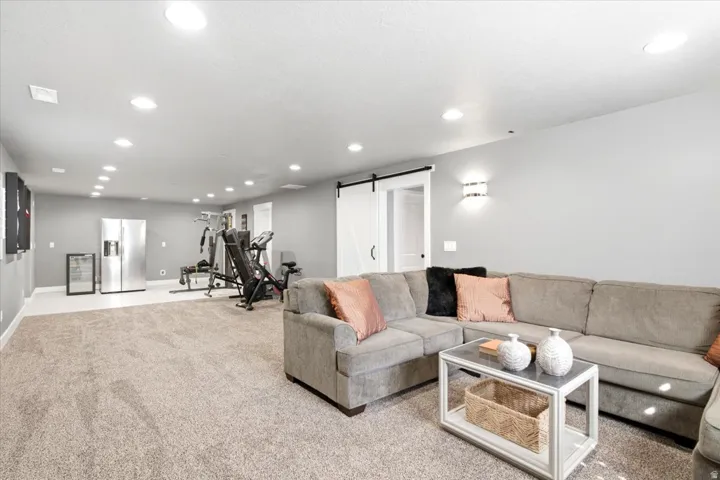 Spacious room featuring neutral carpeting, recessed ceiling lighting, and a modern barn door