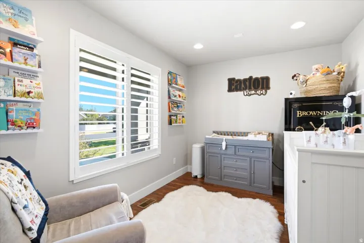 Recessed lighting, wood-finish flooring, white window shutters, and wall-mounted shelving