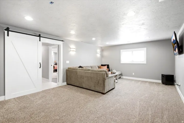 Recessed lighting, light-toned carpeting, and a white sliding barn door with black hardware