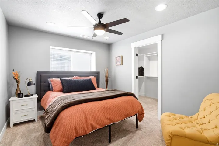 Recessed lighting, ceiling fan, window with blinds, carpeted flooring, and built-in closet shelving