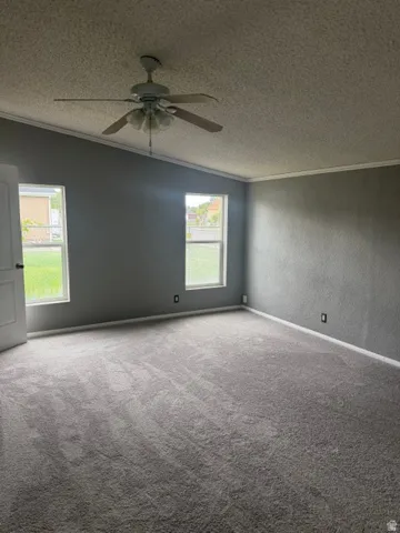 Carpeted room featuring a sloped ceiling, two windows, and a ceiling fan with integrated lighting