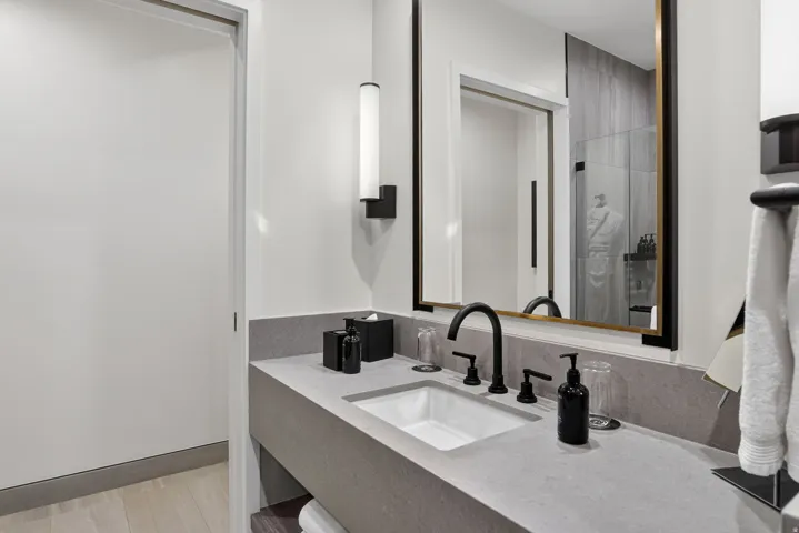 Guest bath vanity with a backlit mirror and glass-enclosed shower in this Canyons Village ski condo.