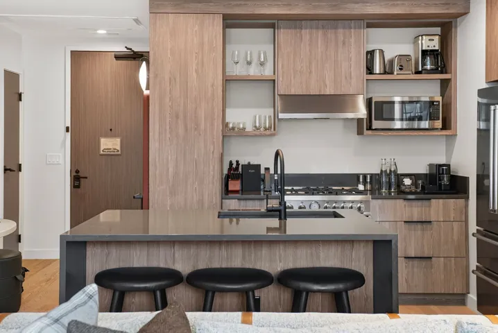 Quartz kitchen island seats three, with integrated appliances and custom cabinetry throughout the residence.