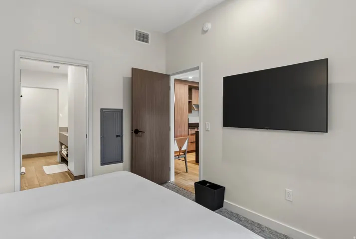 Second bedroom with a mounted television and a doorway to its ensuite bath at Pendry Park City.