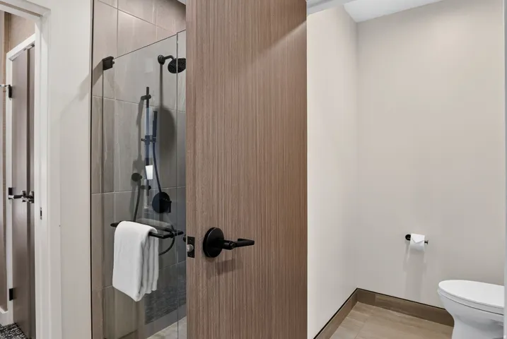Guest bath walk-in shower with wood detailing and matte black fixtures at Pendry Park City.