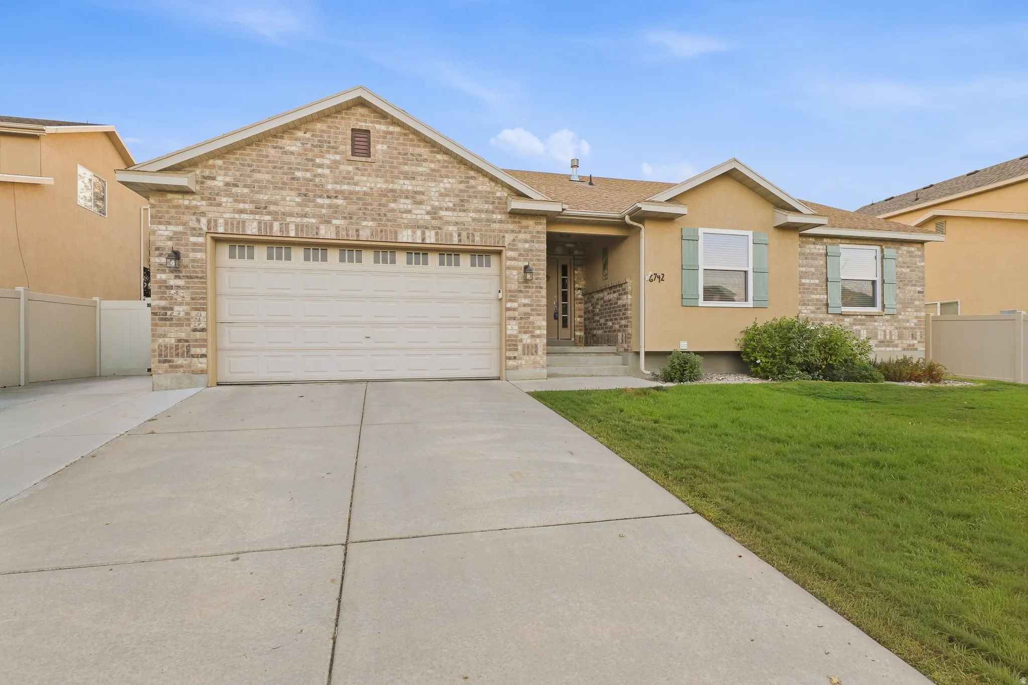 Brick and stucco exterior with a two-car garage, concrete driveway, and front lawn