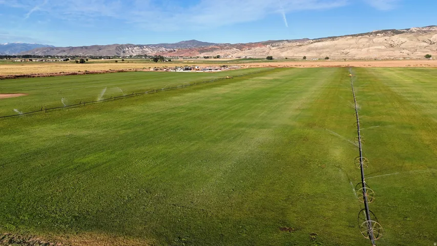 Expansive green fields with irrigation systems, bordered by distant mountains
