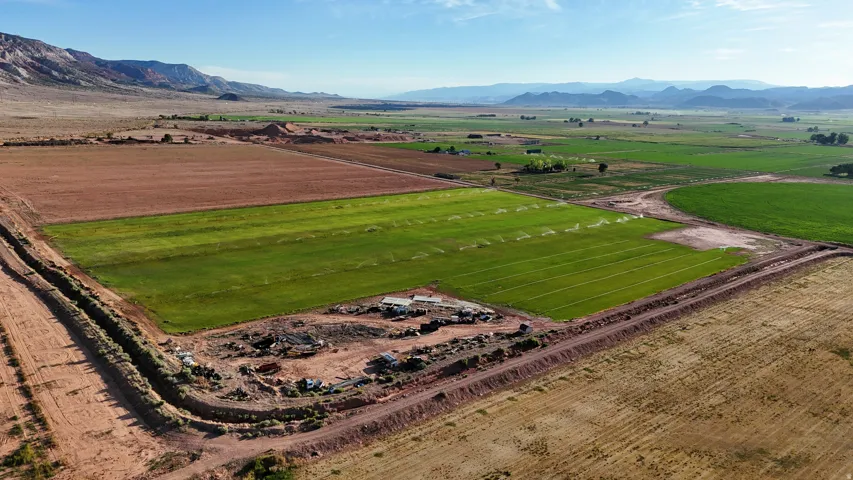 Expansive agricultural land featuring irrigated fields, uncultivated fields, and surrounding mountainous terrain