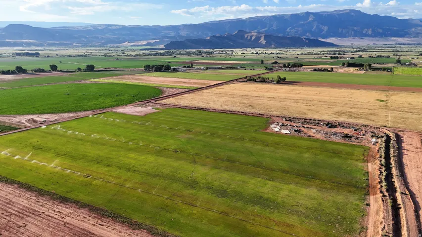 Expansive agricultural land featuring cultivated fields, irrigation systems, and distant mountain ranges
