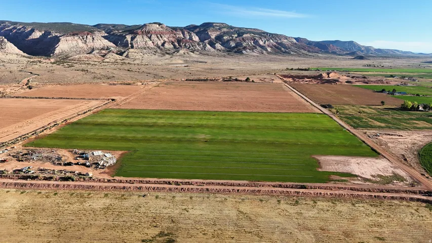 Expansive agricultural land featuring a verdant cultivated field and surrounding arid terrain