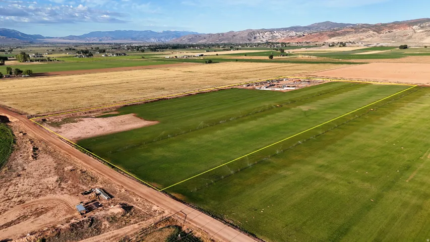 Expansive agricultural land featuring a verdant field, visible irrigation system, and surrounding natural landscape