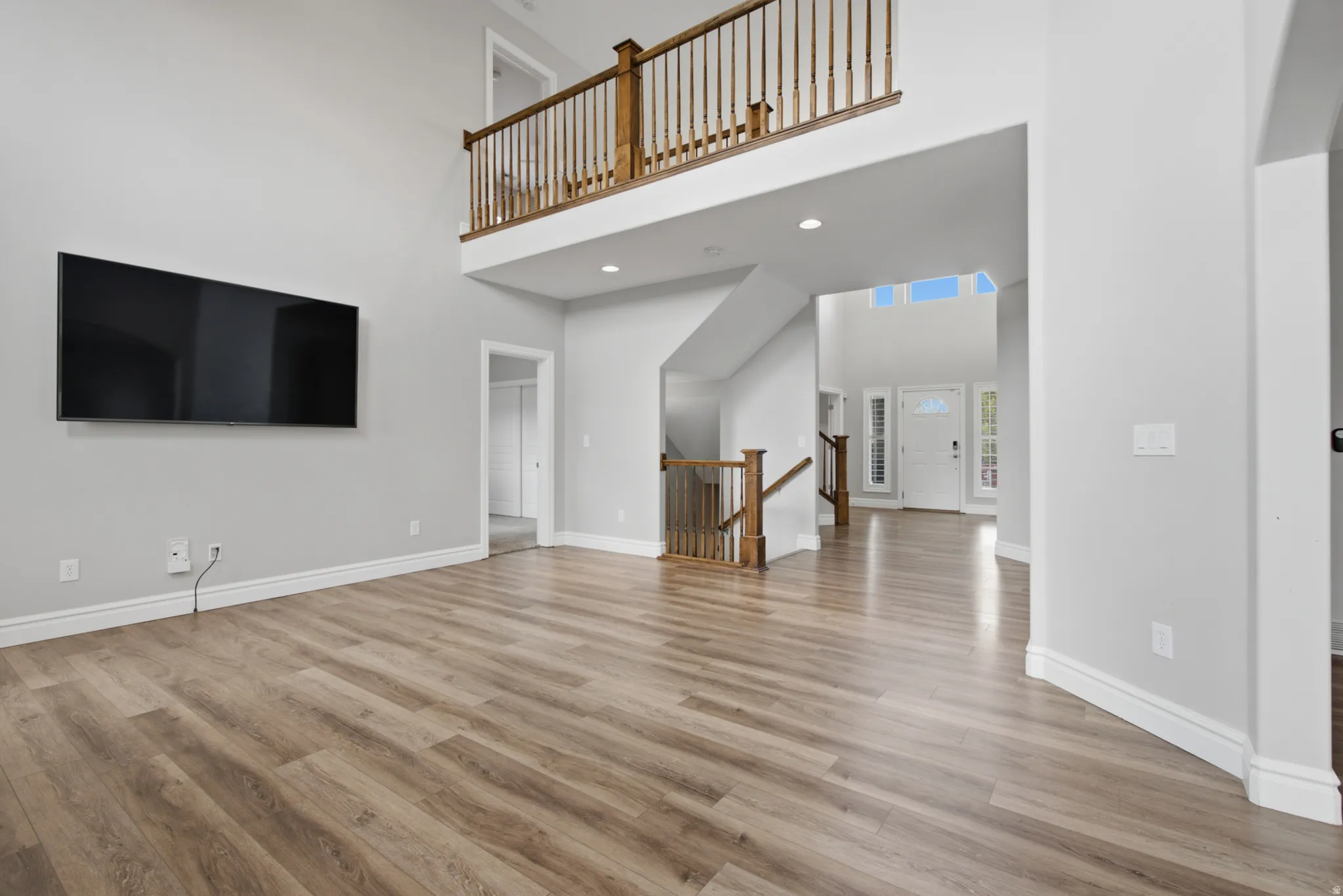 Two-story foyer with transom windows, wood-finish flooring, and natural wood railings