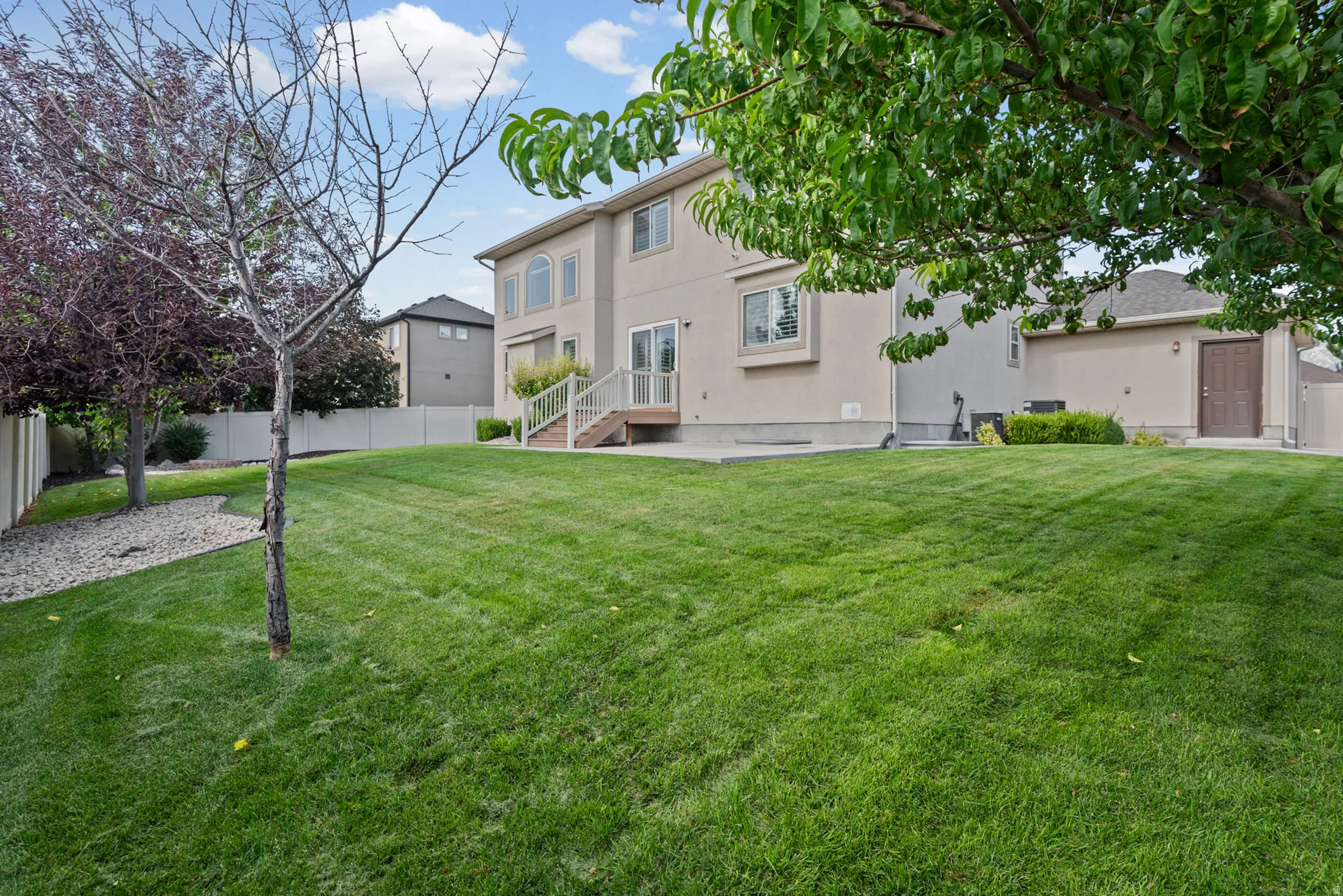 Expansive backyard with a lush lawn, mature trees, and privacy fencing