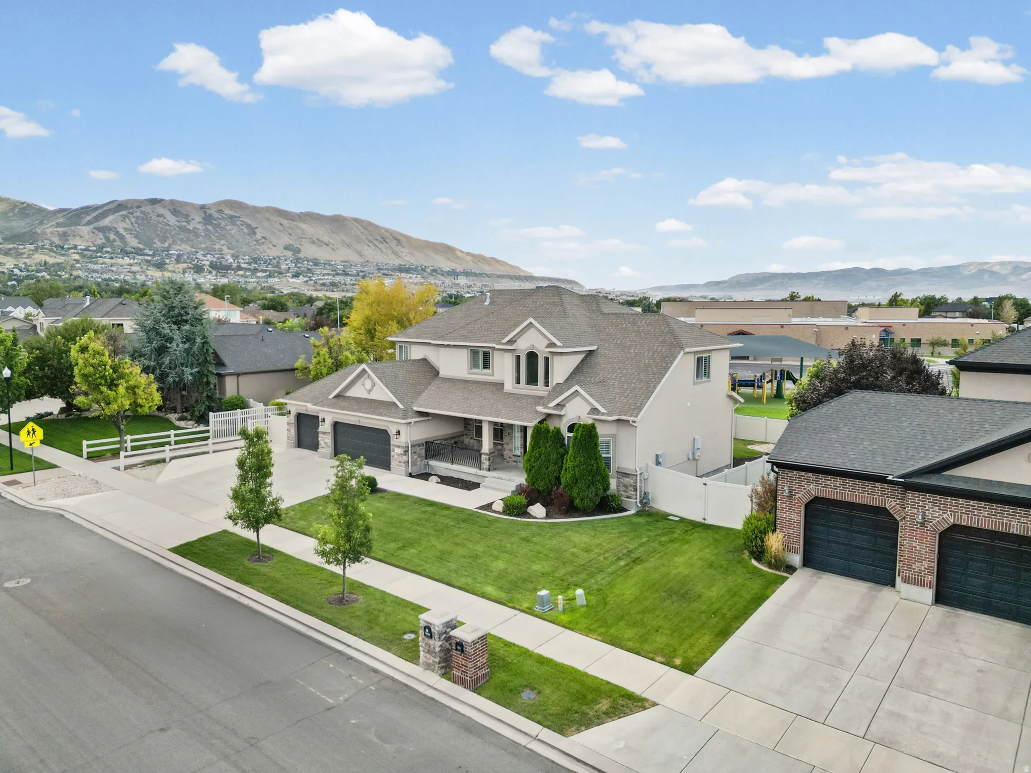 Stucco exterior with stone accents, covered front porch, attached three-car garage, and a manicured front lawn