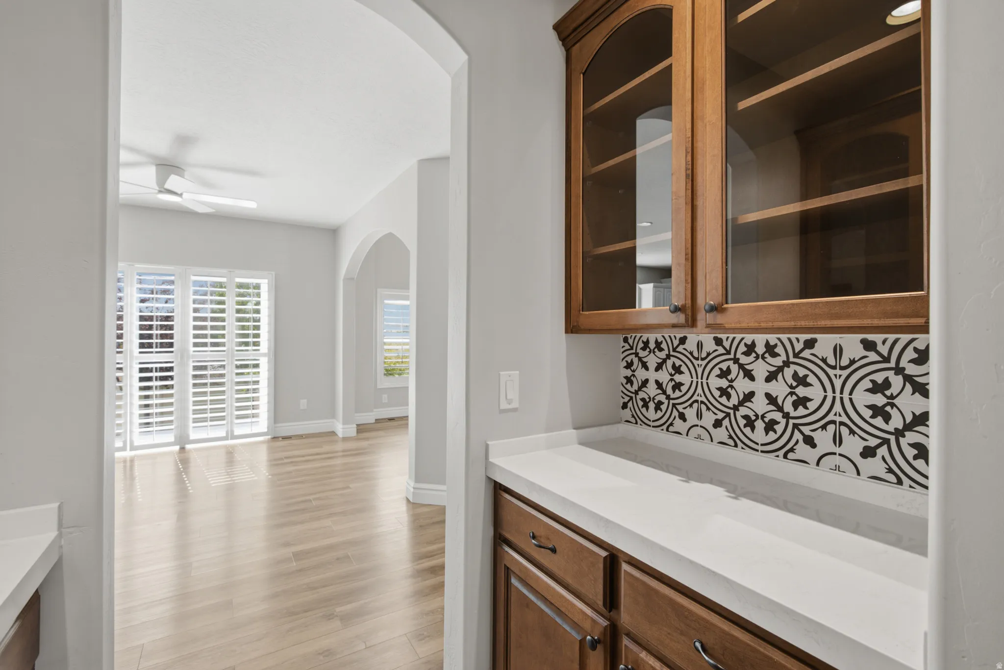 Built-in cabinetry with glass-front uppers, patterned tile backsplash, and light-toned countertops