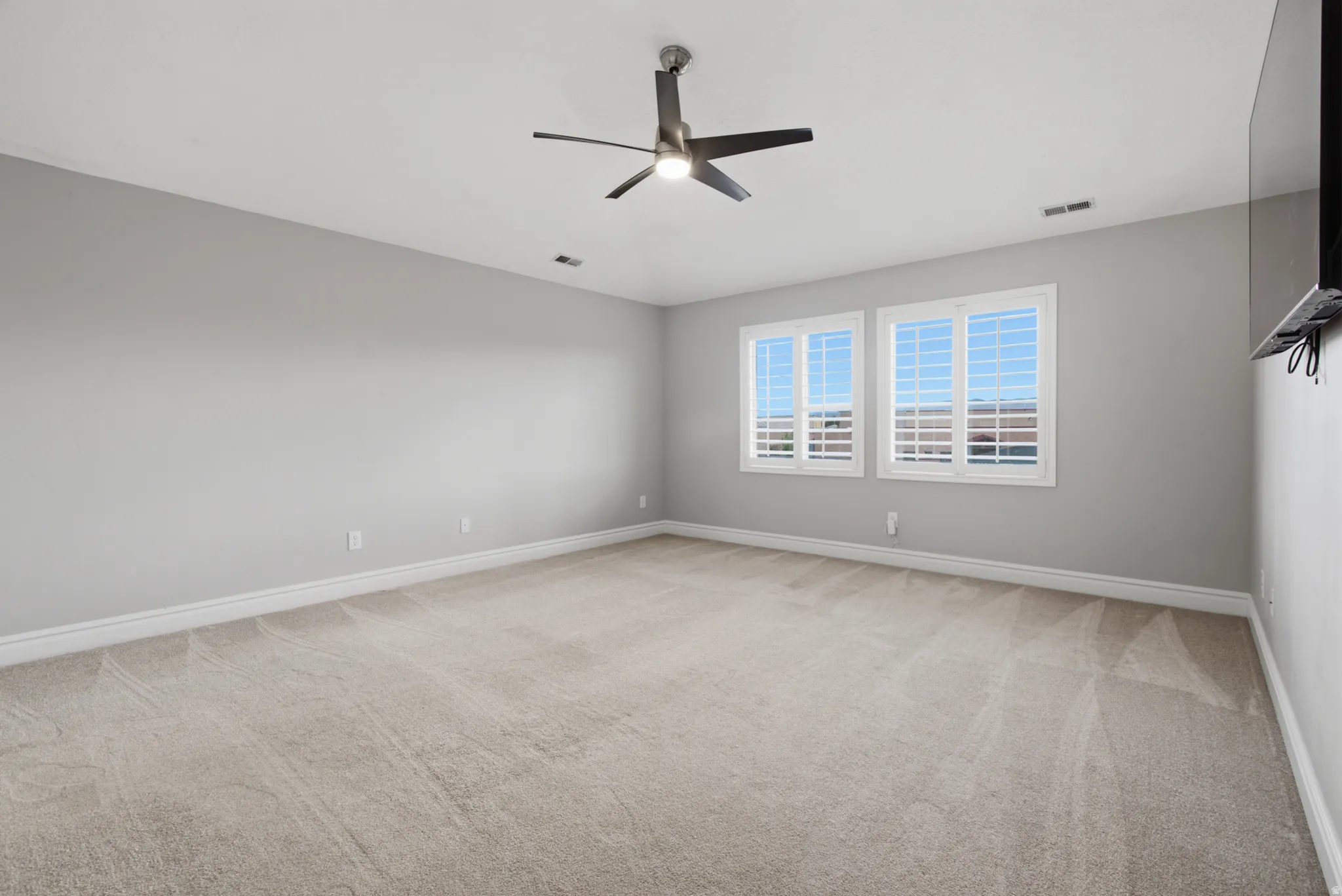 Recessed lighting, ceiling fan, dual windows with plantation shutters, and neutral carpeting