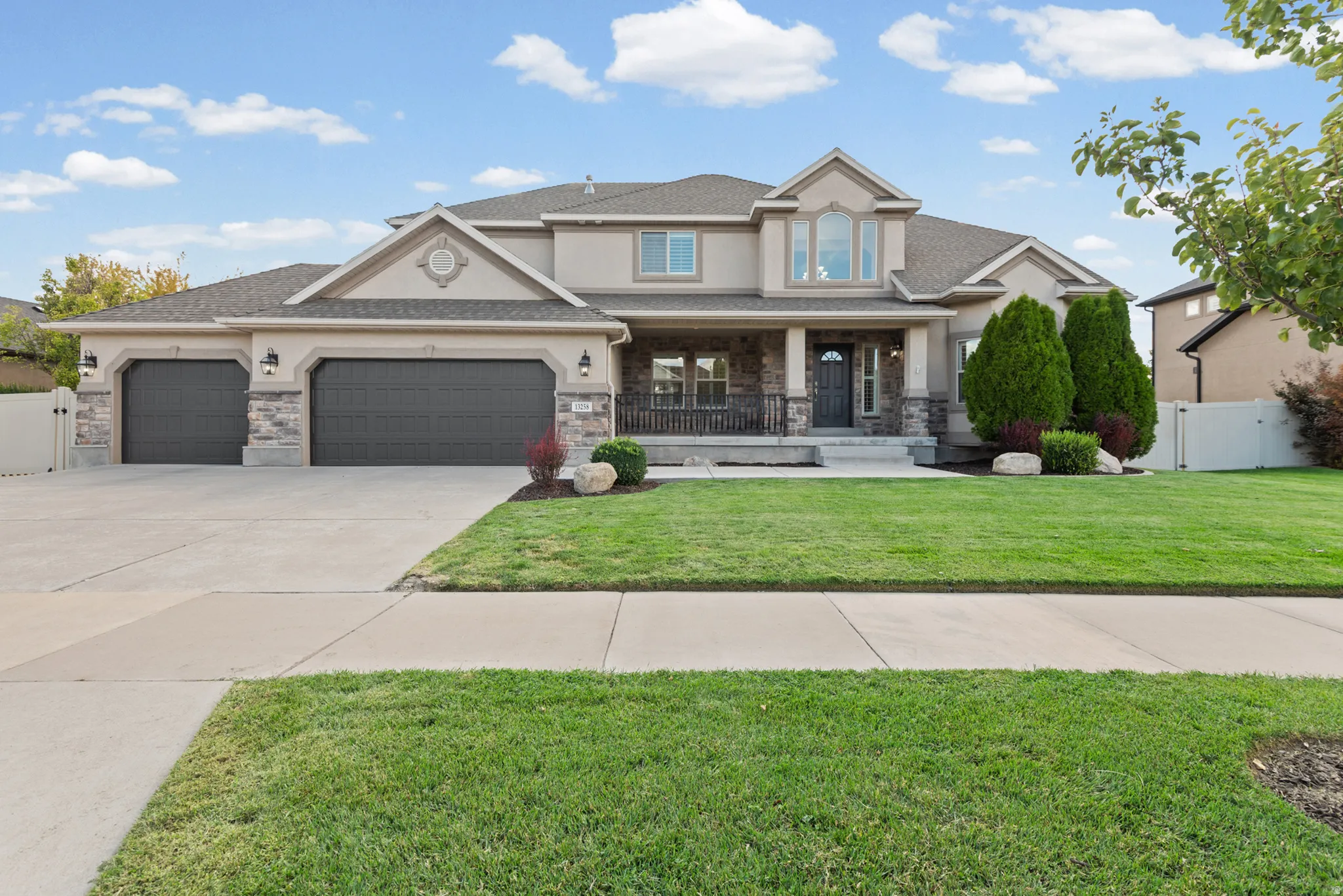 Stucco exterior with stone accents, a covered front porch, and a three-car garage
